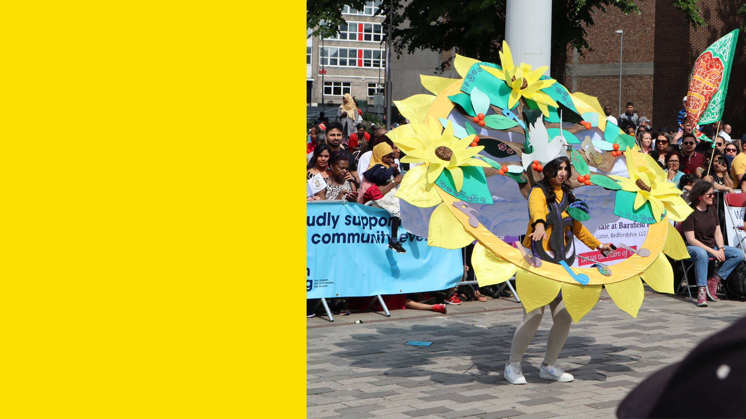 The Carnival queen wearing a massive hoop that looks like a giant sunflower. She is dancing in front of the crowds