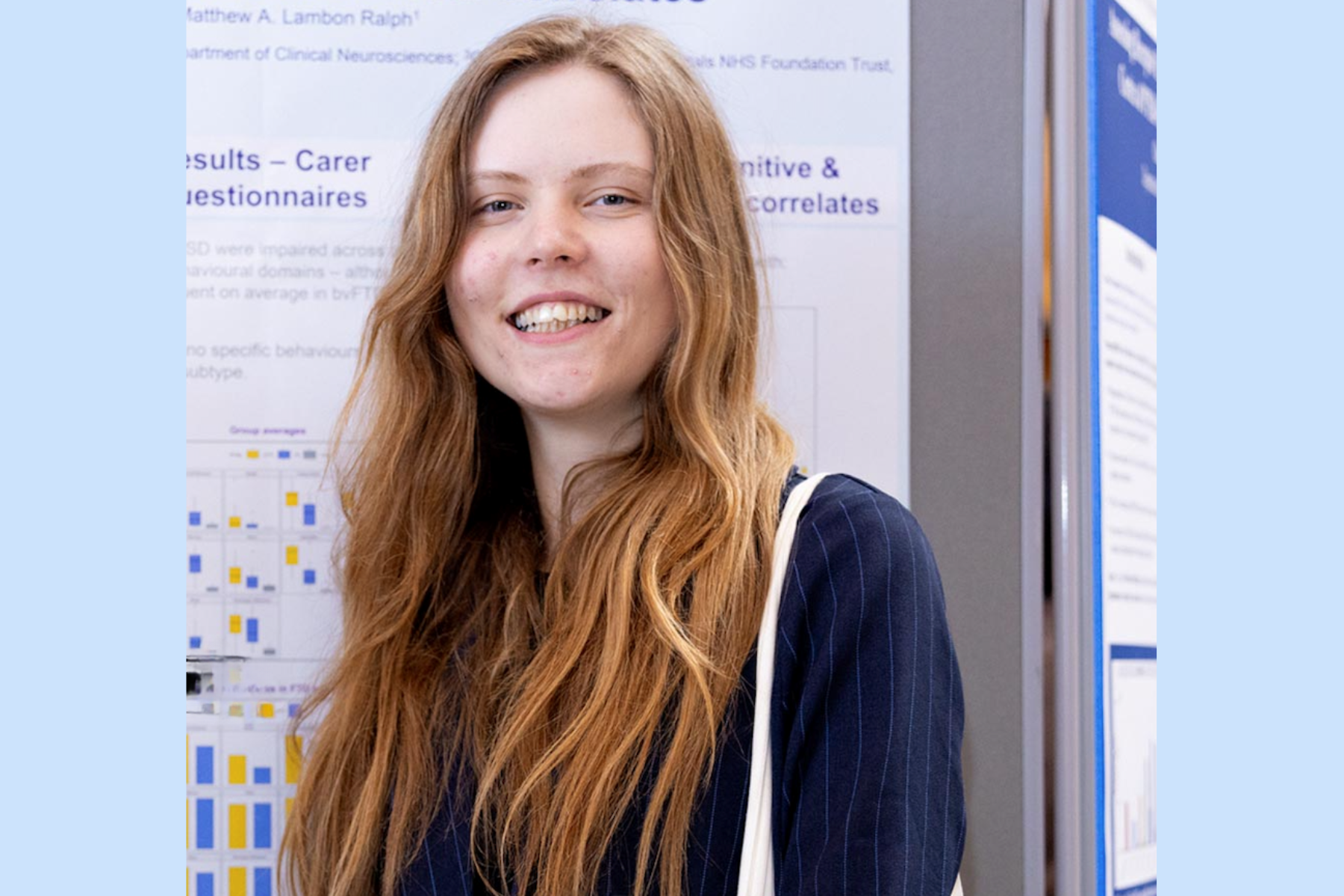 A young woman with very long strawberry blond hair, smiling and wearing a navy pinstripe jacket