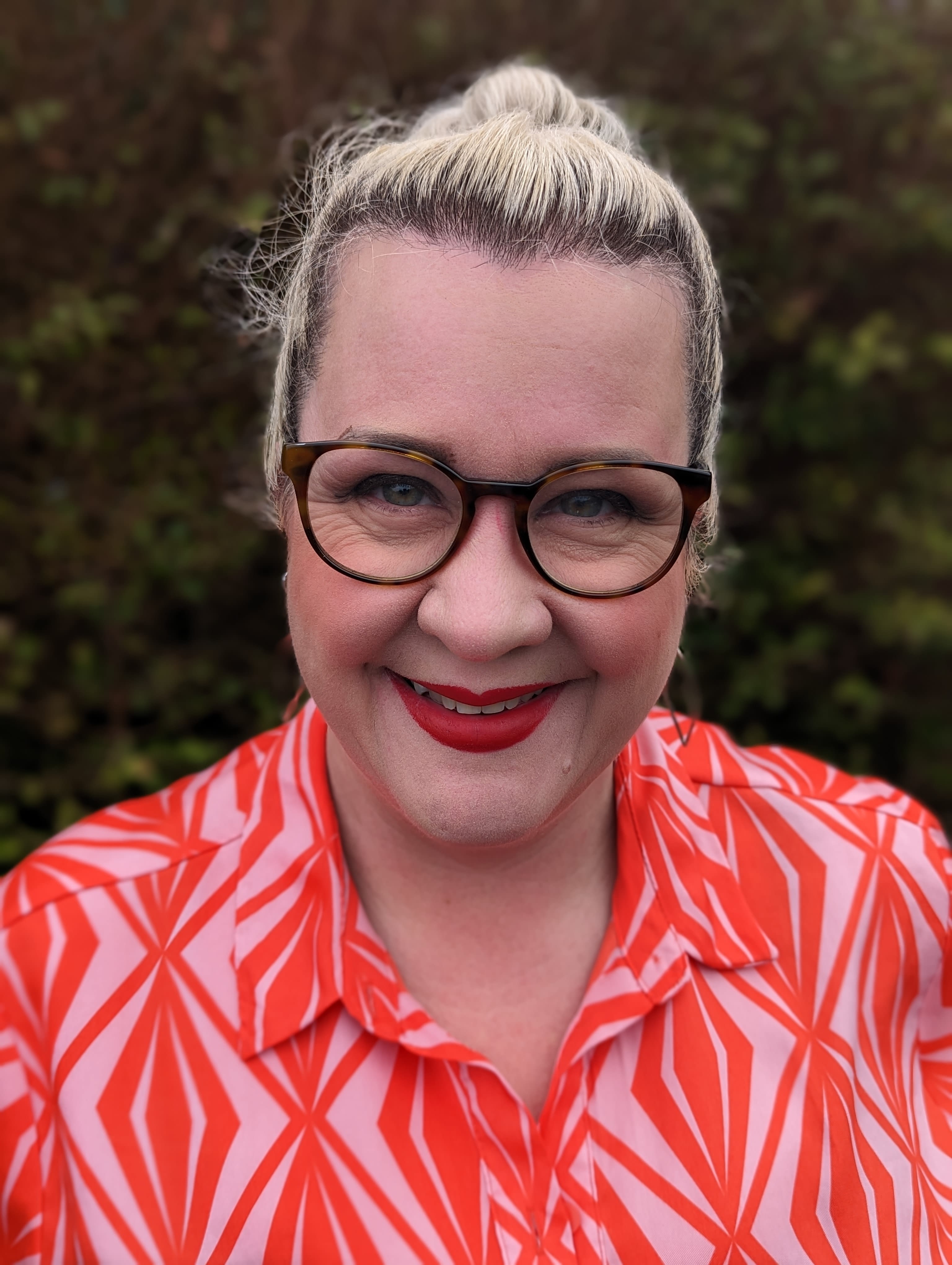 A lady in a patterned shirt smiling