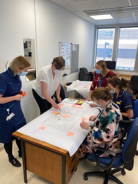 Healthcare staff around a table studying the hospital designs and sticking on post its
