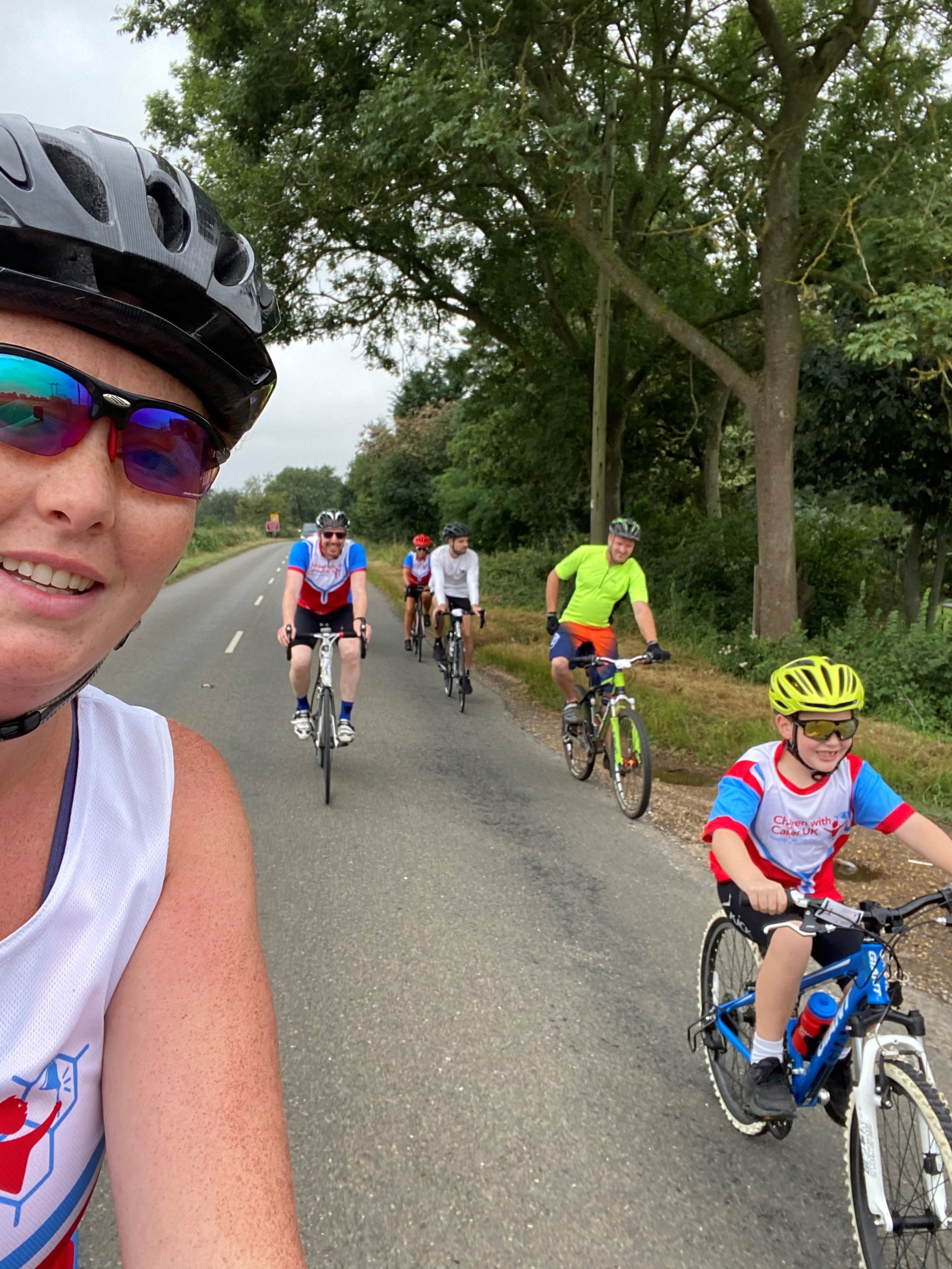 Niall in a bright yellow bike helmet leads a line of cyclists for sponsored bike ride