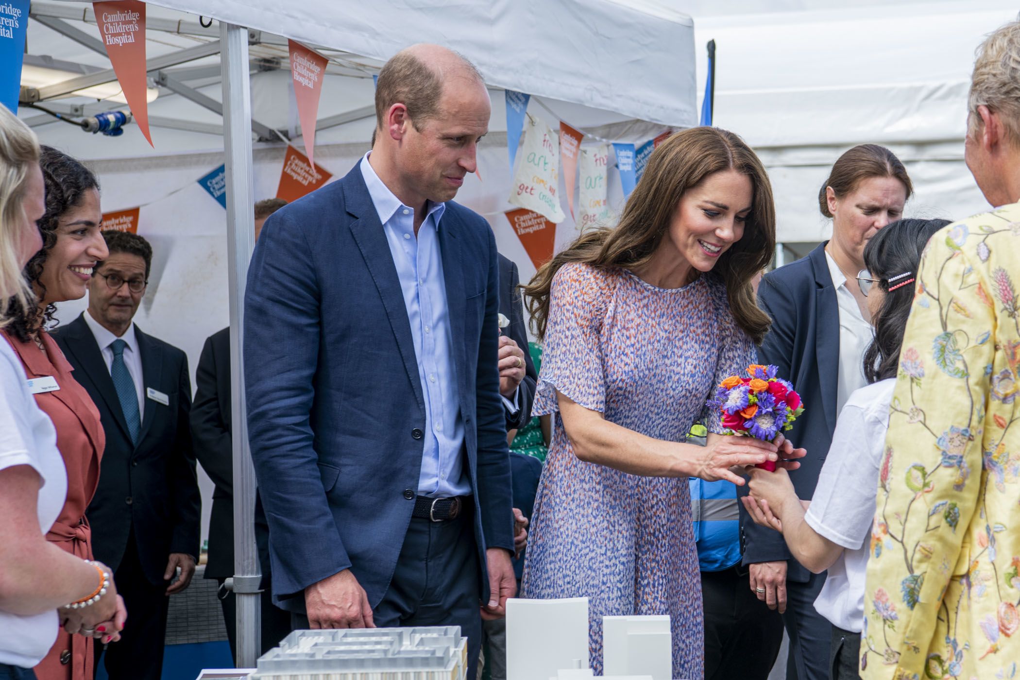 A teenager presents a colourful posey of flowers to the Duke and Duchess of Cambridge
