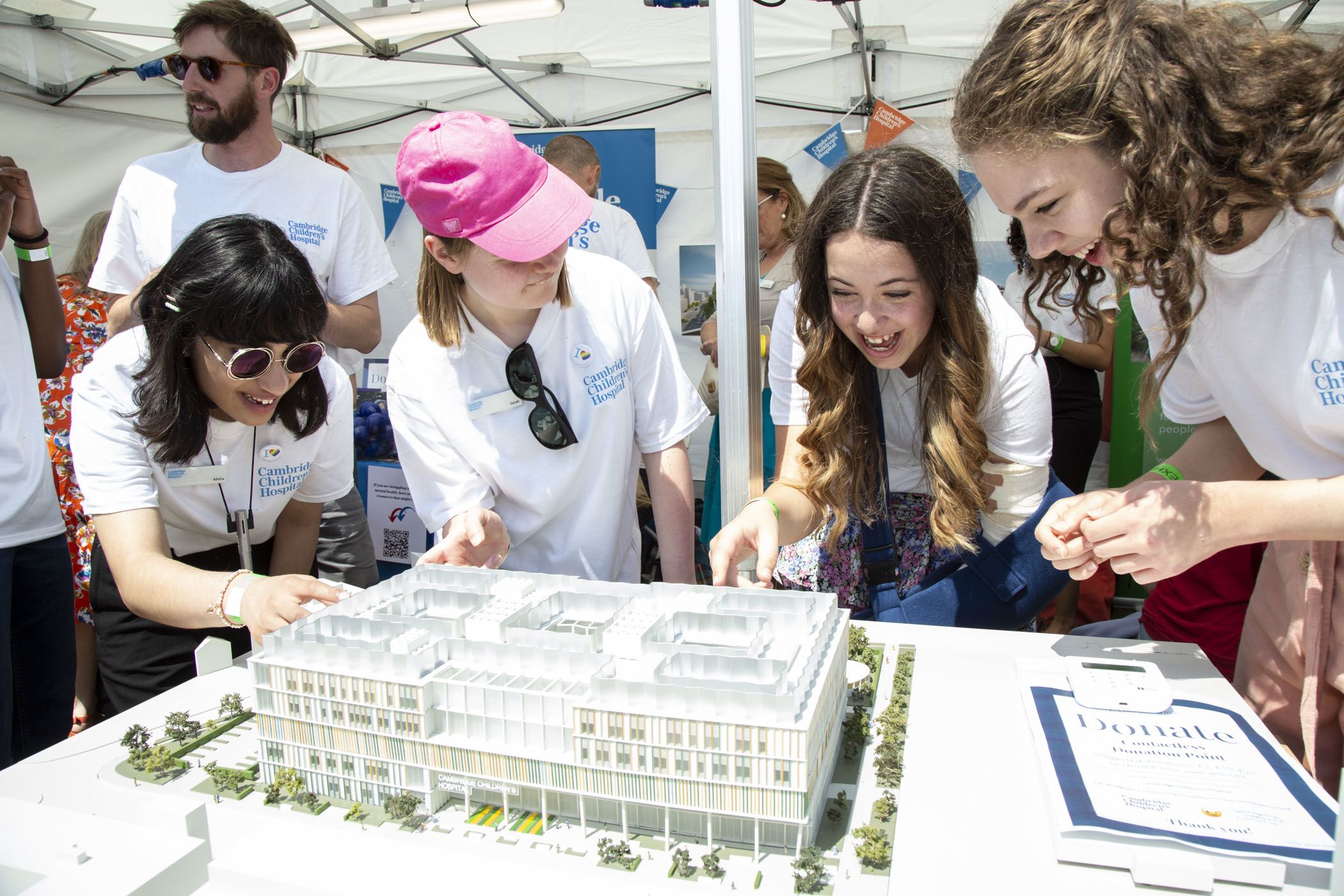 four teenagers gather around a model of the new Cambridge children's hospital