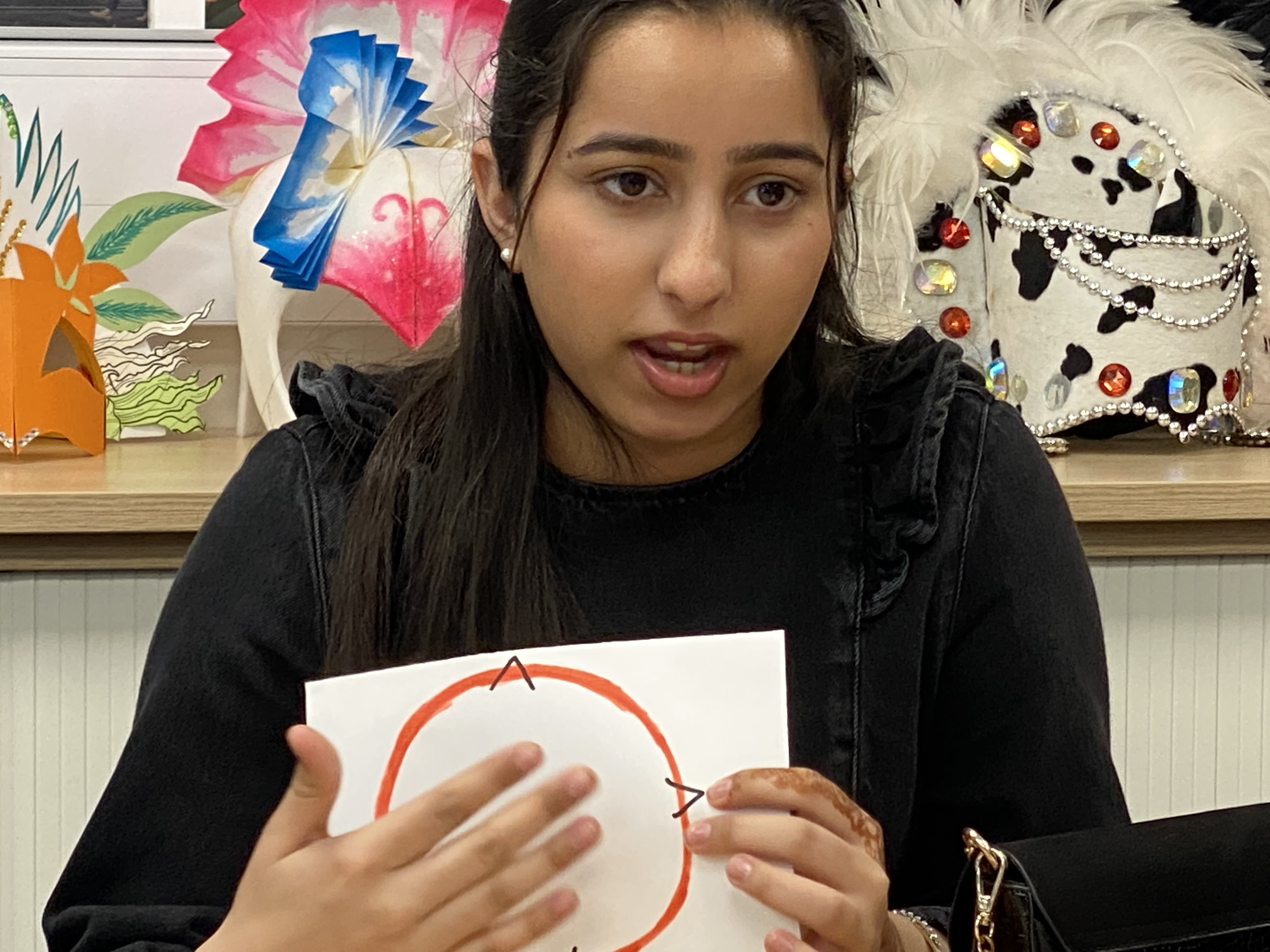 A girl holding up a picture of a red circle