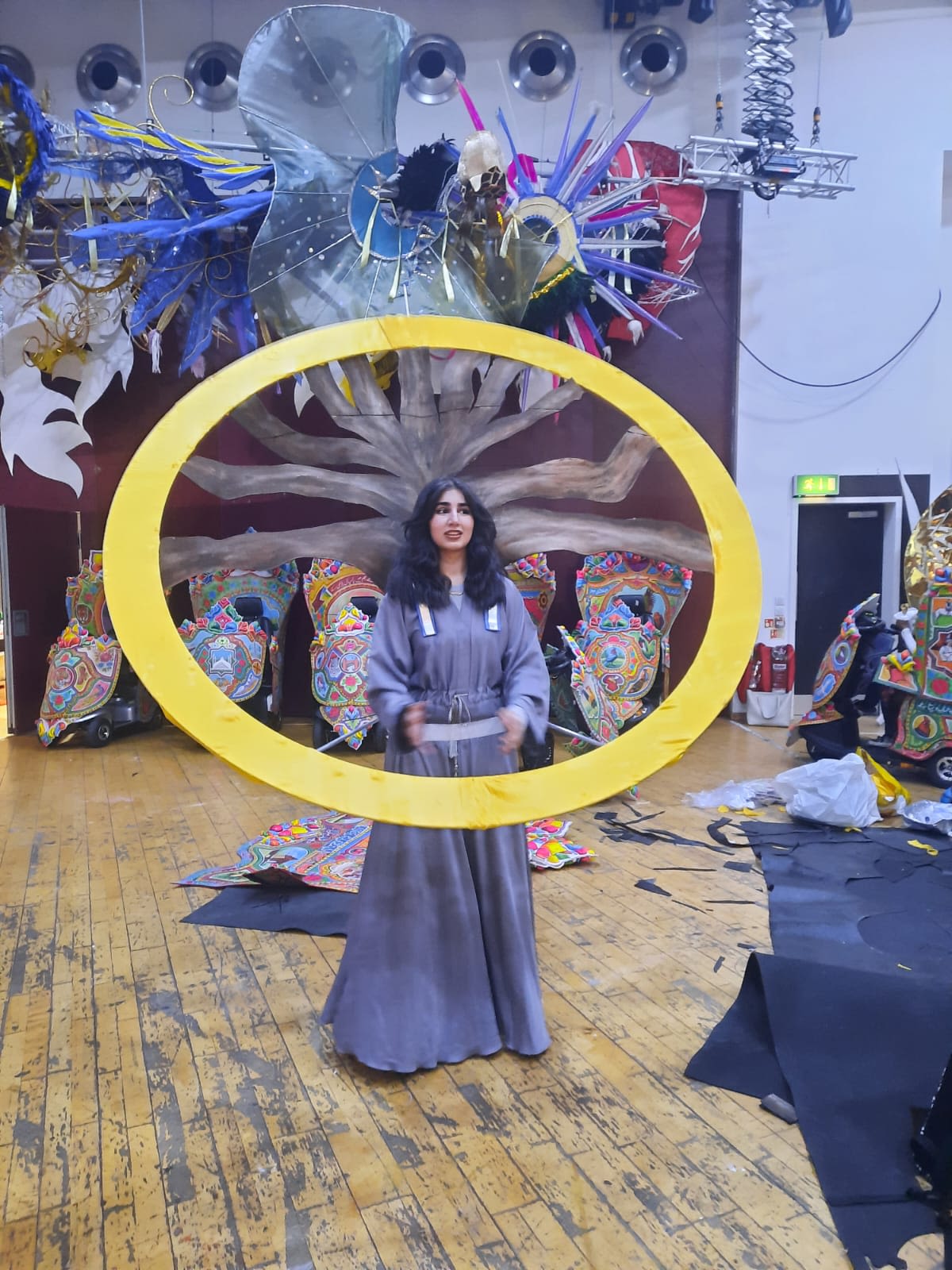 A girl in a long flowing purple dress wearing a huge yellow hoop that will eventually form the basis of a giant sunflower