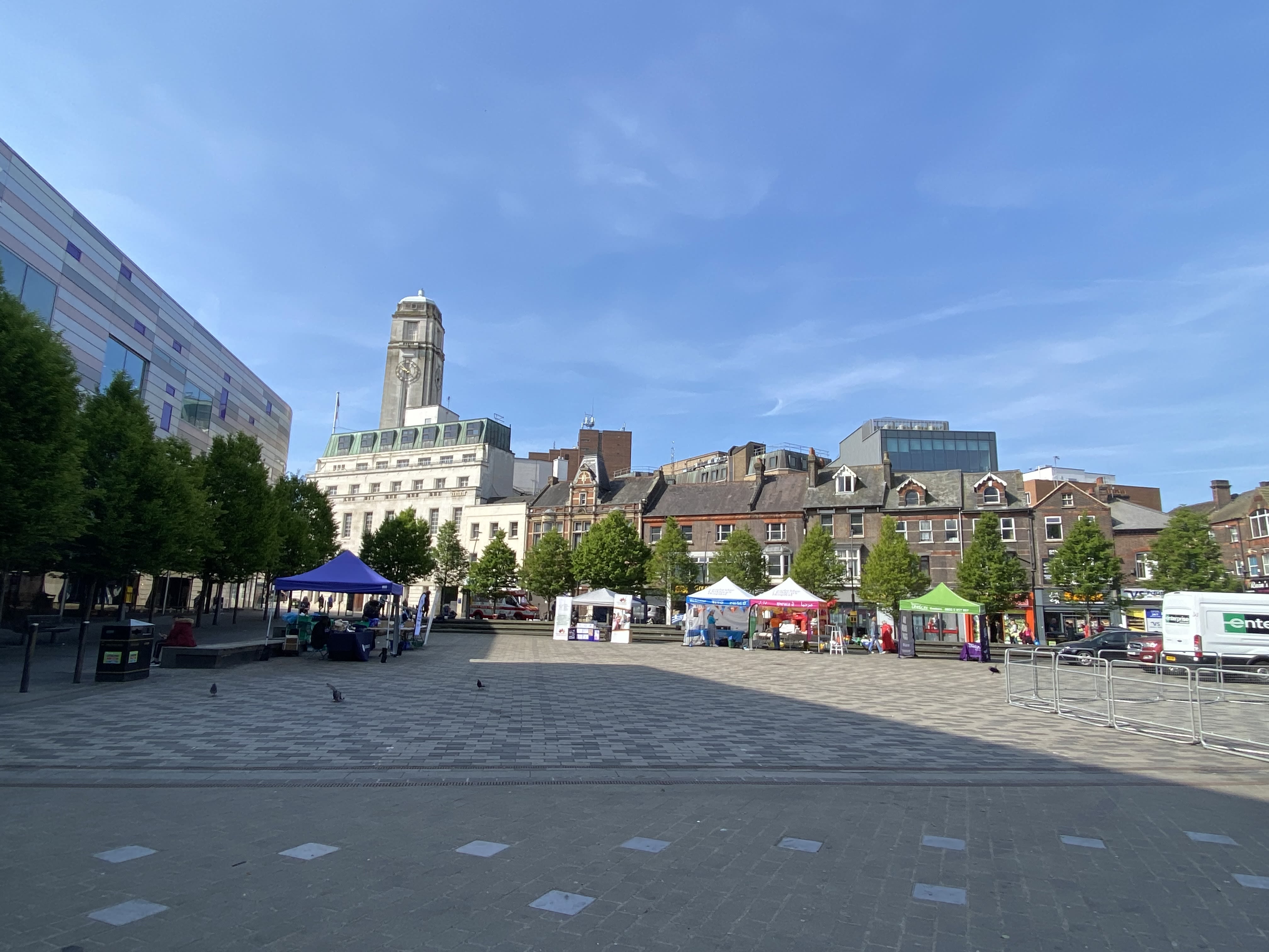A town square with marquees and a town hall in the background. The Sky is very blue