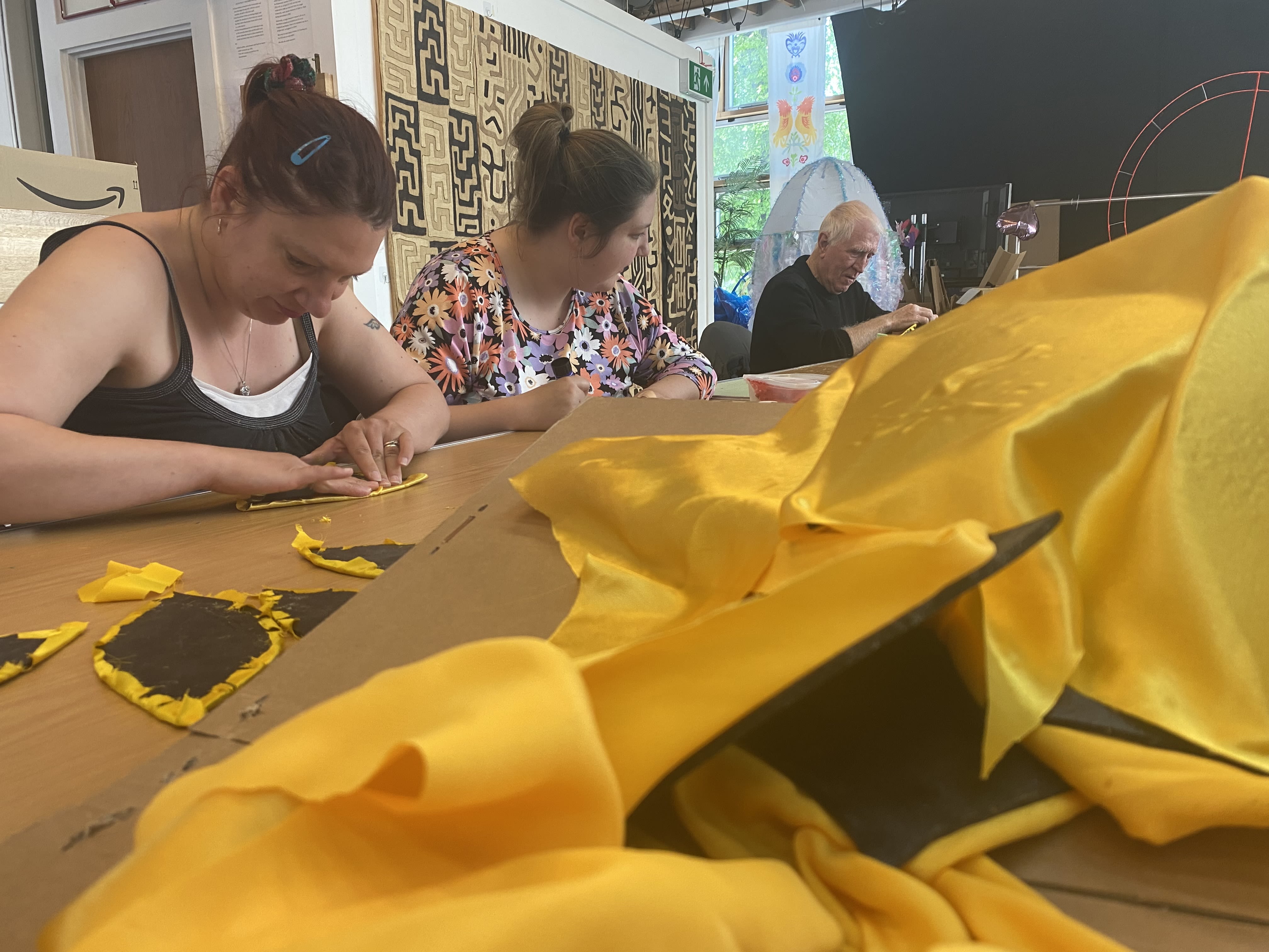 People sticking yellow petals together with fabric and foam