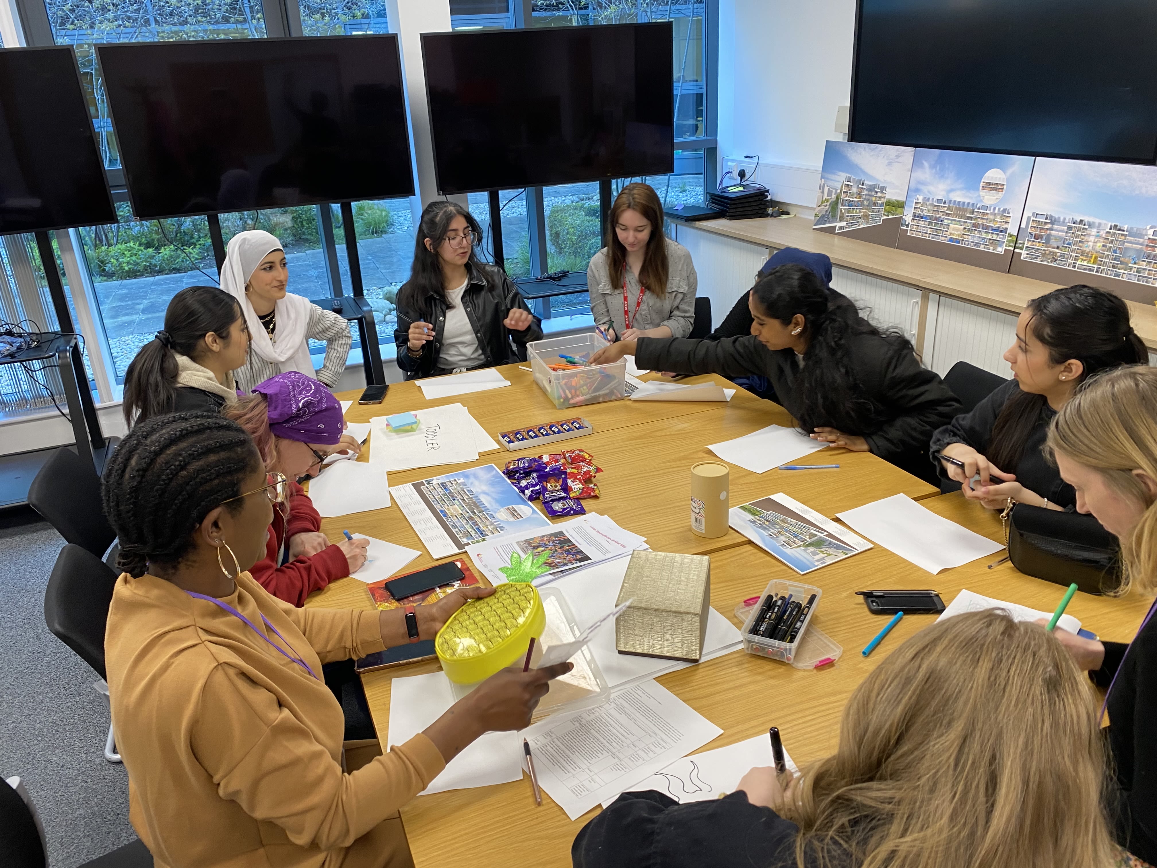 A group of teenagers around a table, talking and drawing