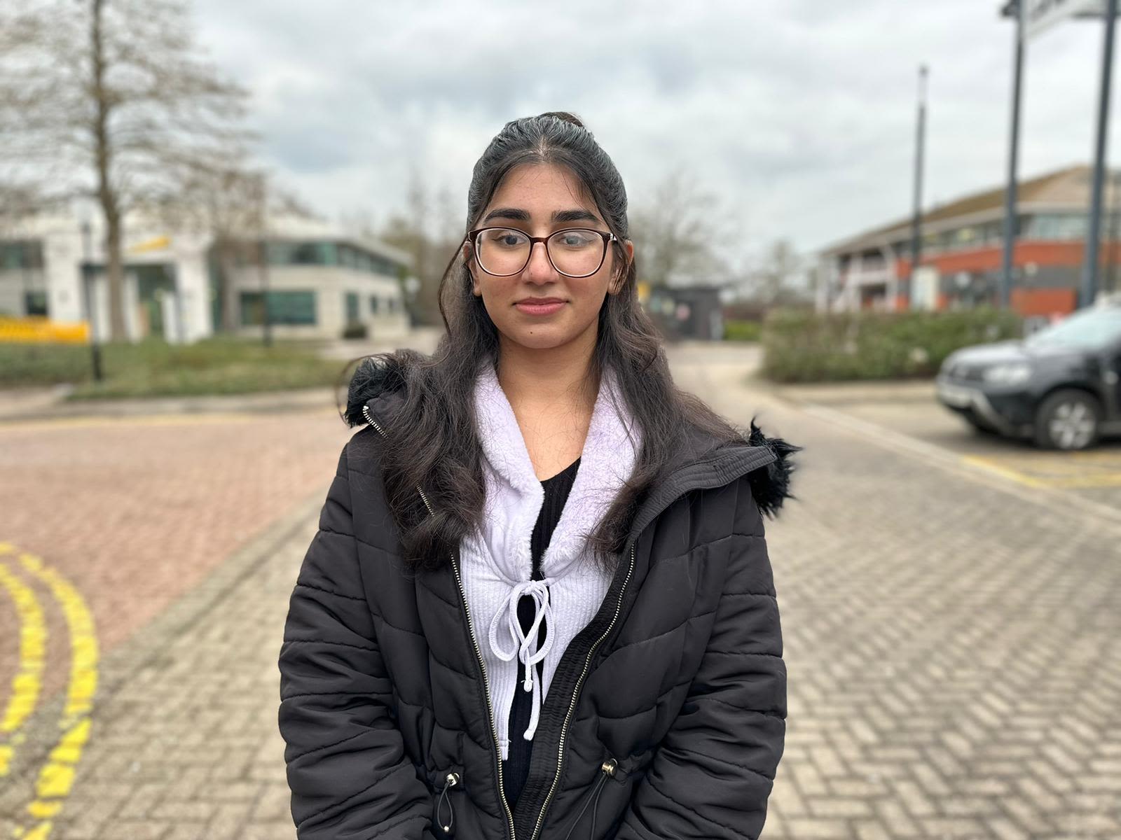 A teenage girl with long brown hair and a black coat